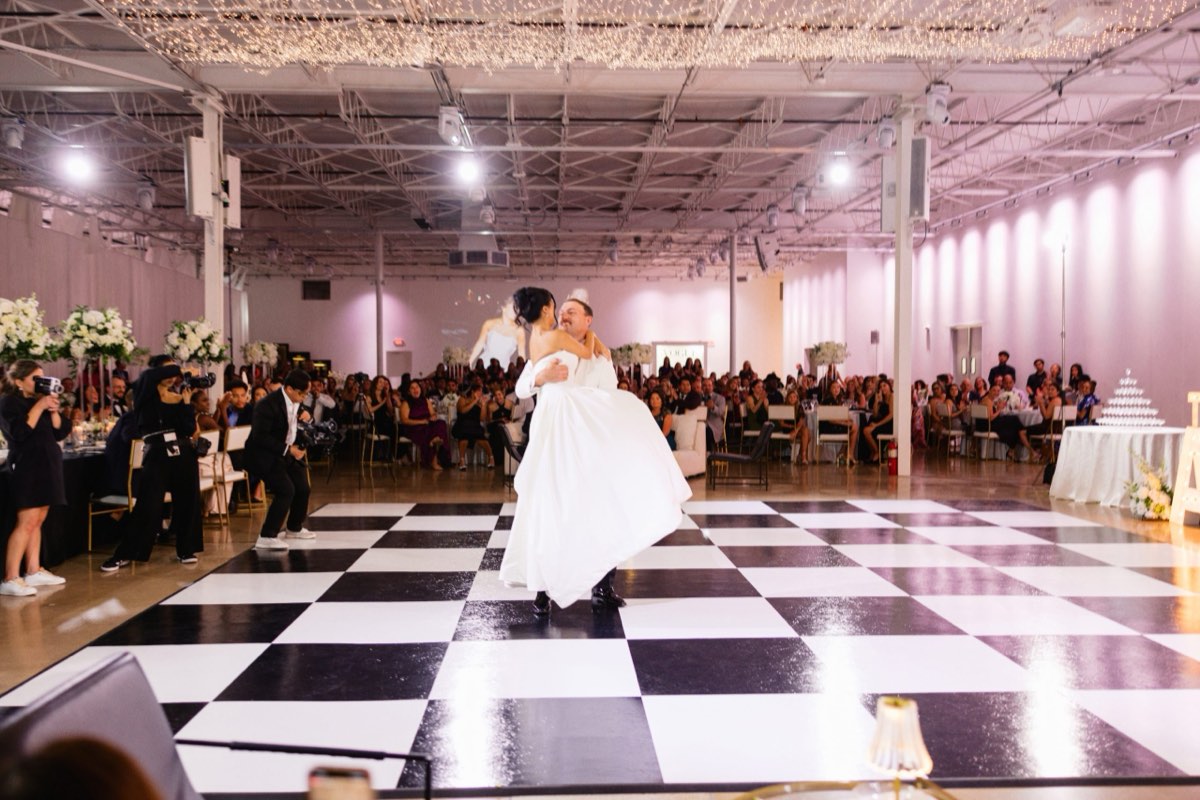 Bride and groom sharing a first dance on a black-and-white checkered dance floor at Astoria Event Venue